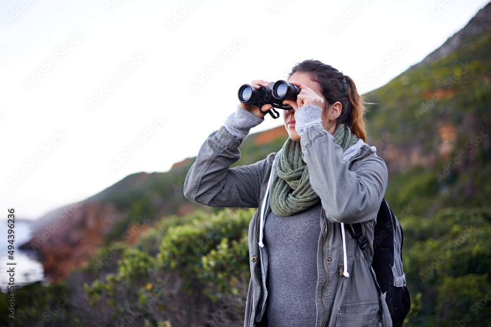 哇，景色太棒了……一位迷人的年轻女子在徒步旅行时用双筒望远镜拍摄的照片。