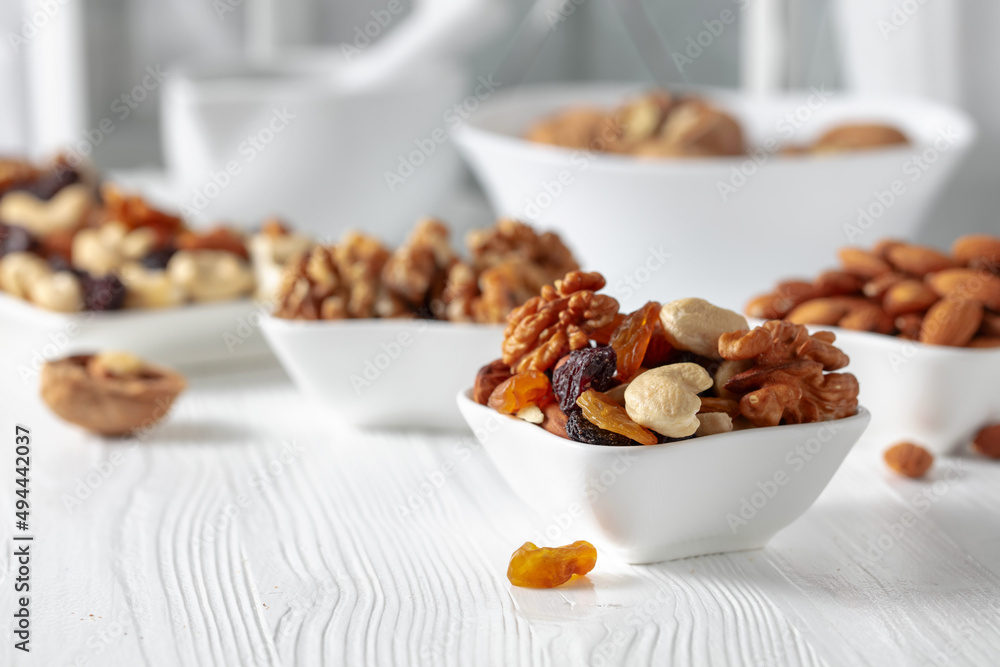 Mix of nuts and raisins on a white wooden table.