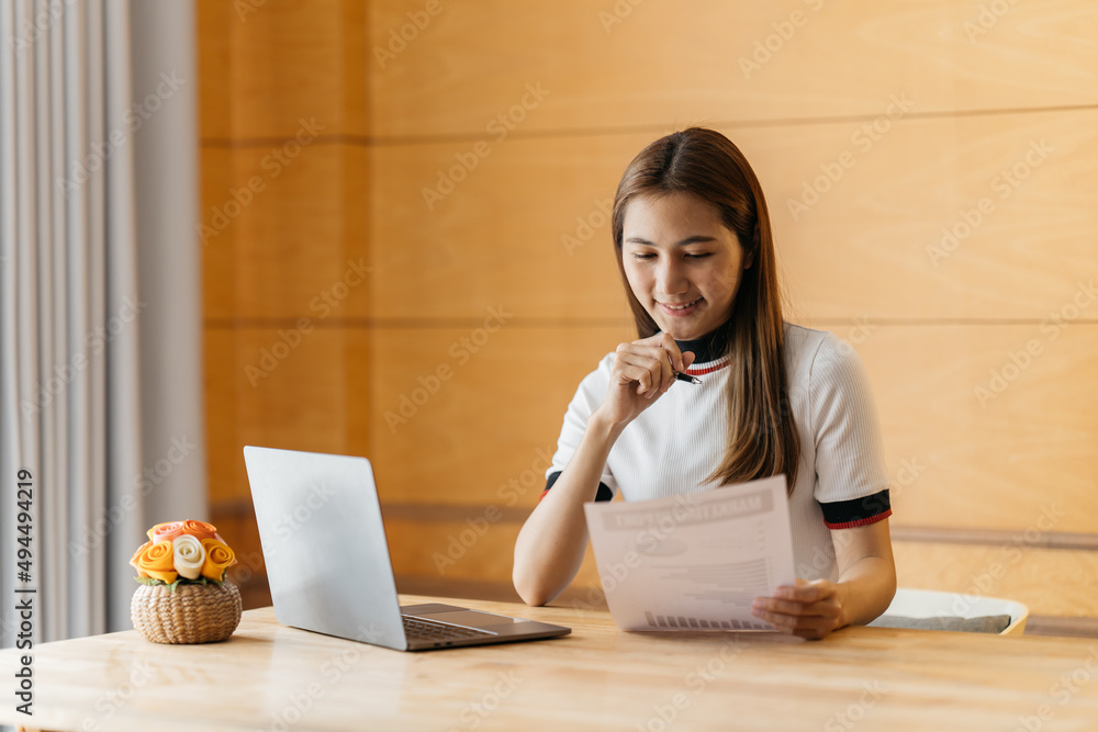 微笑的年轻女子使用笔记本电脑，坐在家里的沙发上，漂亮女孩购物或在线聊天