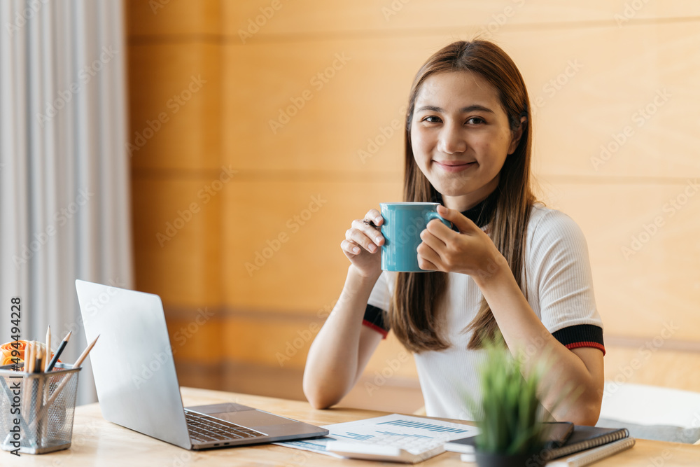 年轻女子在寒冷的冬天用笔记本电脑放松并喝一杯热咖啡或茶