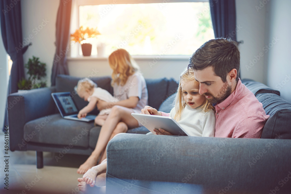 They keep their home connected. Shot of an adorable little girl using a digital tablet with her fath