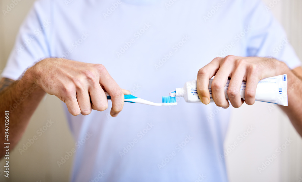 Brushing twice a day keeps the cavities away. Shot of a man applying toothpaste to his toothbrush.