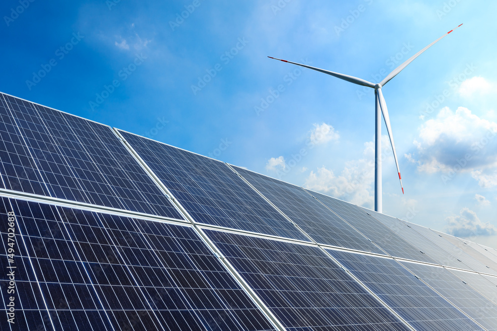 Solar panels and wind turbines landscape under blue sky. Green energy concept.