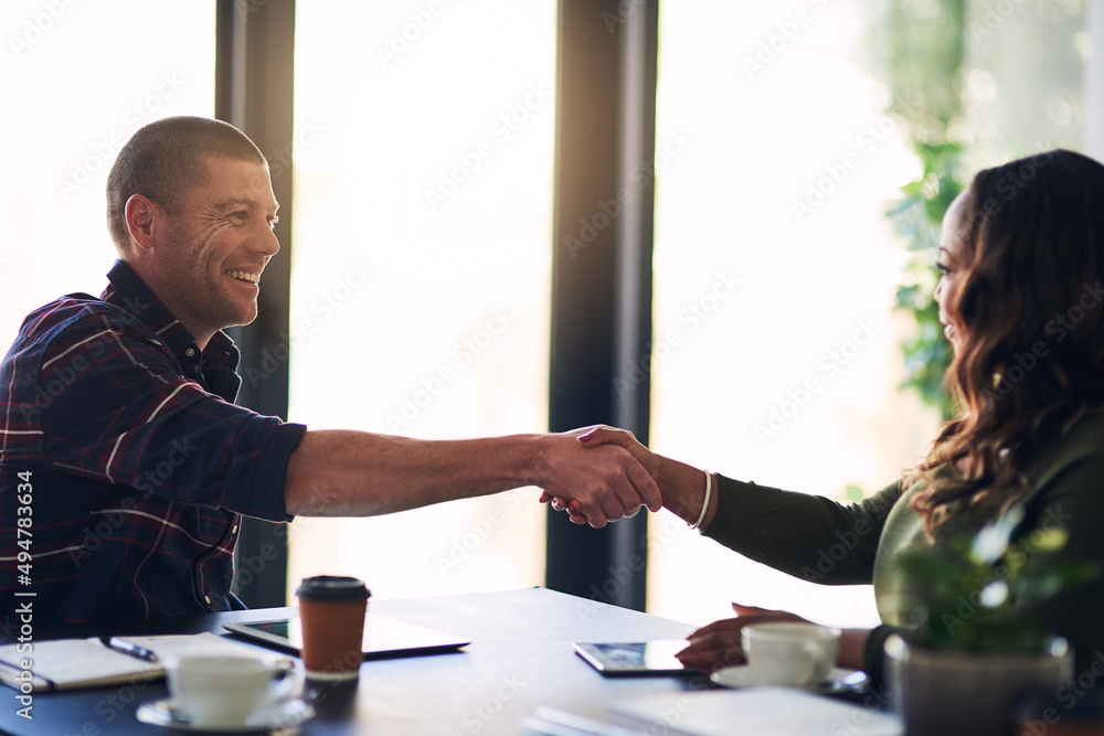 Its a pleasure doing business with you. Shot of two cheerful businesspeople shaking hands in agreeme