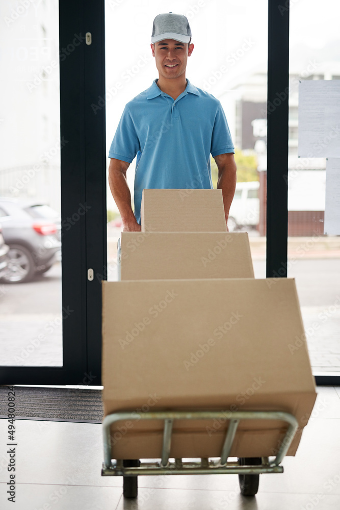 No delivery is too big for us to handle. Portrait of a courier pushing a trolley of boxes while maki