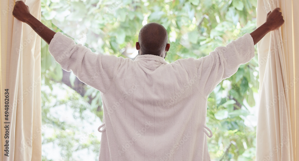 Lets get this day started. Shot of a young man opening curtains at home.