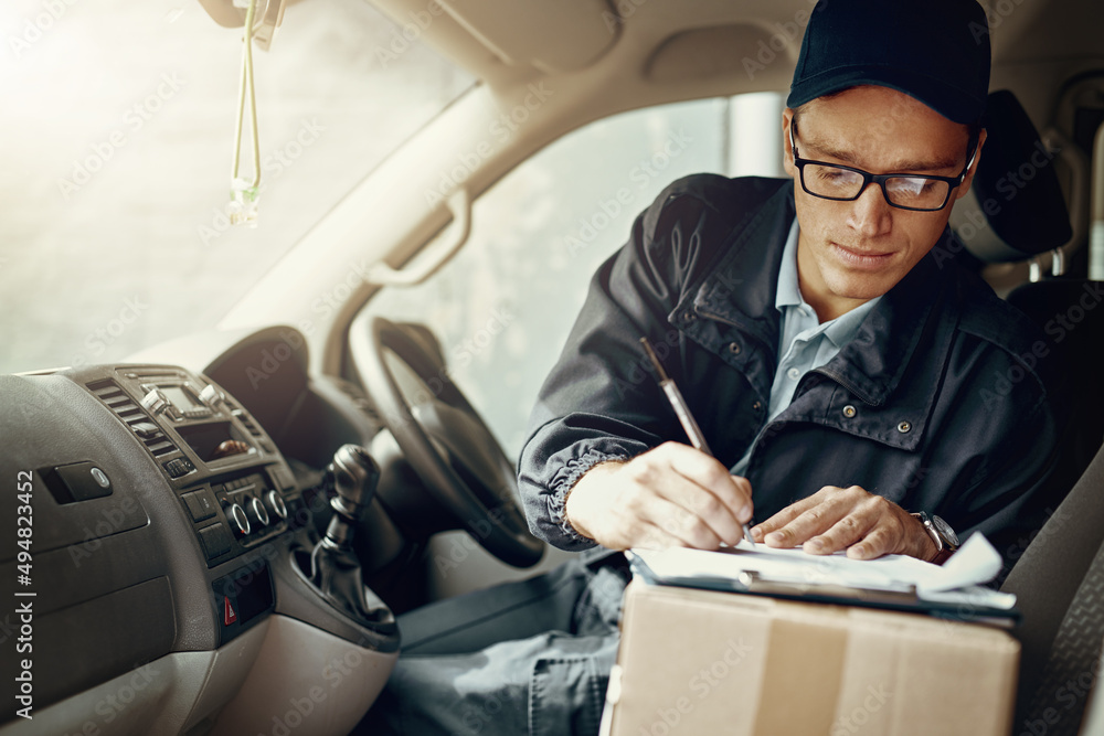 Checking where his next delivery stop is. Shot of a courier making deliveries in his van.