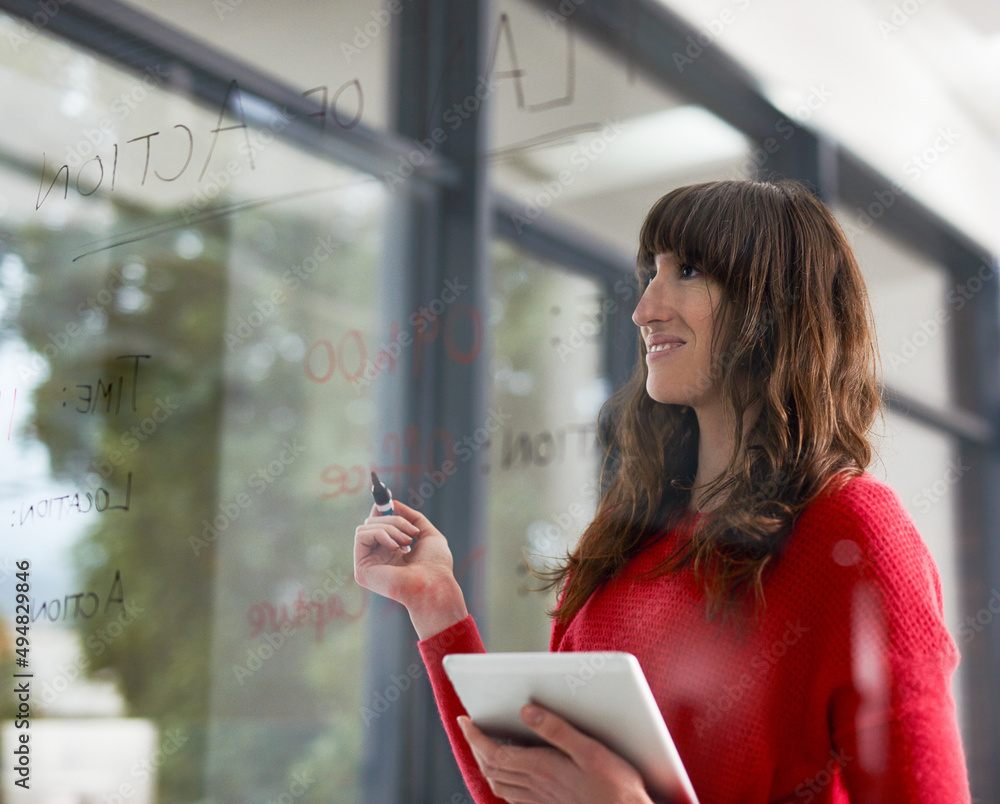 Coming up with ideas. Shot of businesspeople writing on a glass wall in the office.