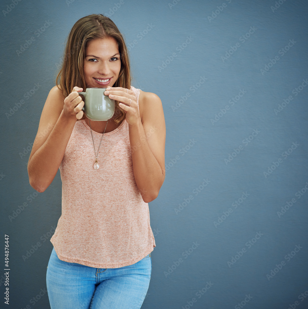 Good days start with me and tea. Studio portrait of a young woman drinking a beverage against a gray