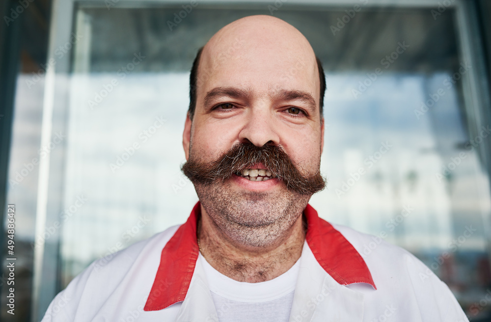 Hes a friendly butcher. Shot of a butcher at his store.