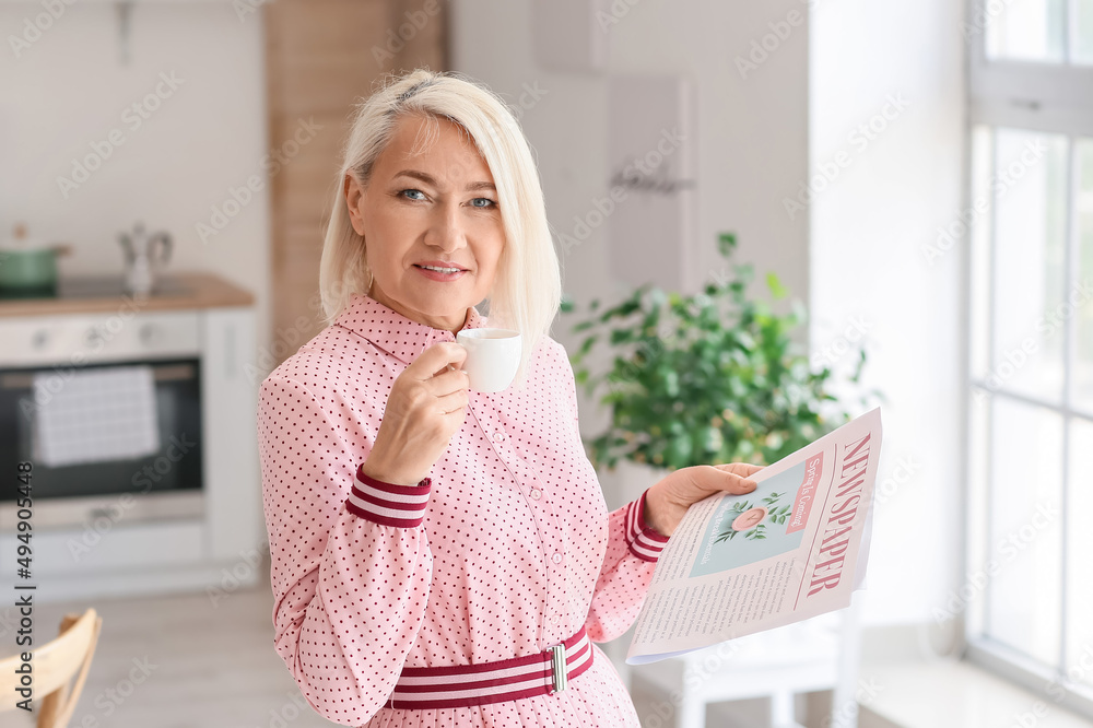 漂亮的成熟女人在家里喝着咖啡看报纸