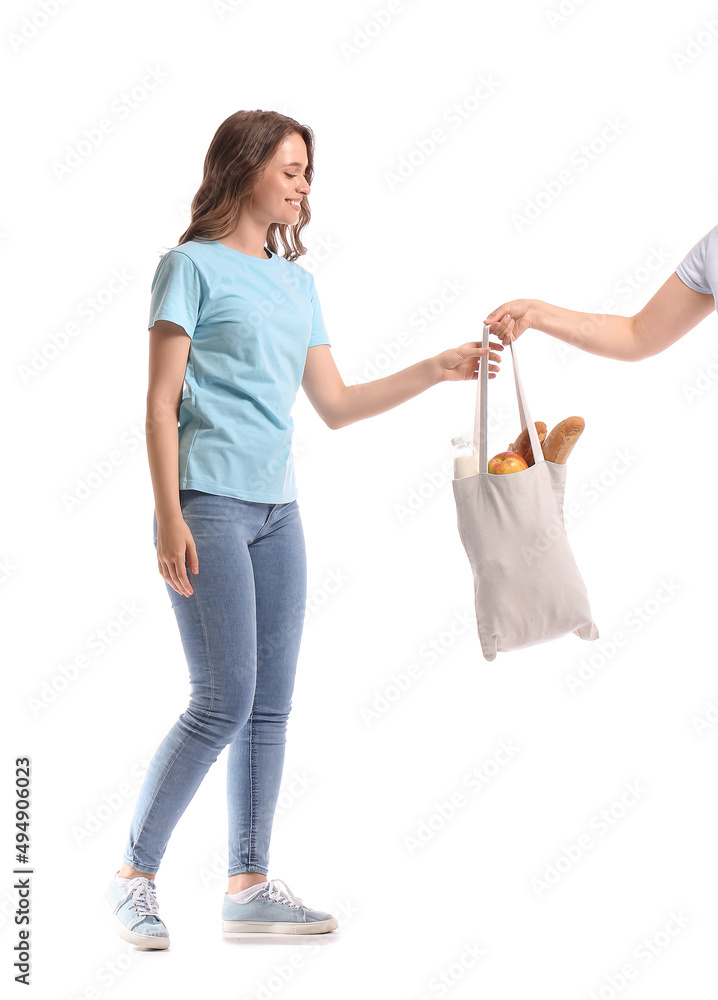 Young woman taking eco bag with food and drink on white background