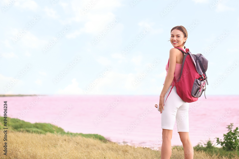 Young tourist with backpack near pink lake