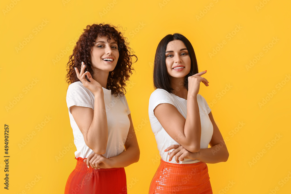 Beautiful smiling sisters on color background