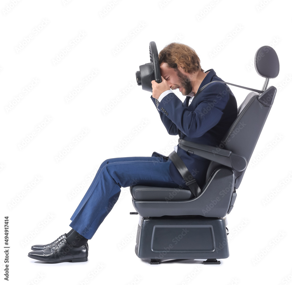 Stressed businessman in car seat and with steering wheel isolated on white