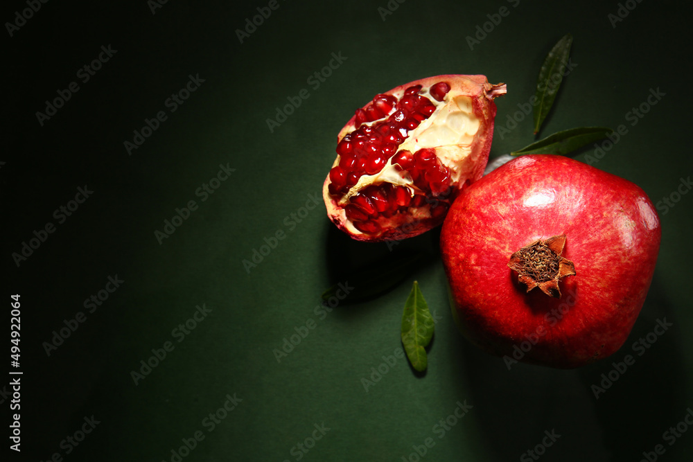 Tasty ripe pomegranates on dark green background