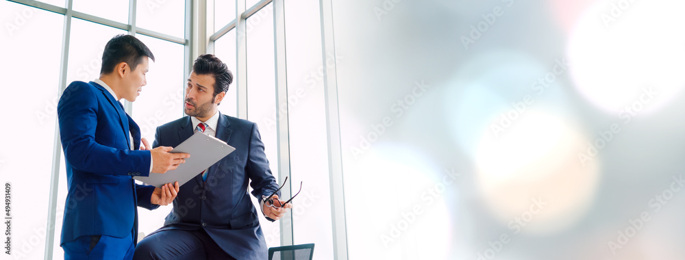 Two business people talk project strategy at office in widen view meeting room. Businessman discuss 