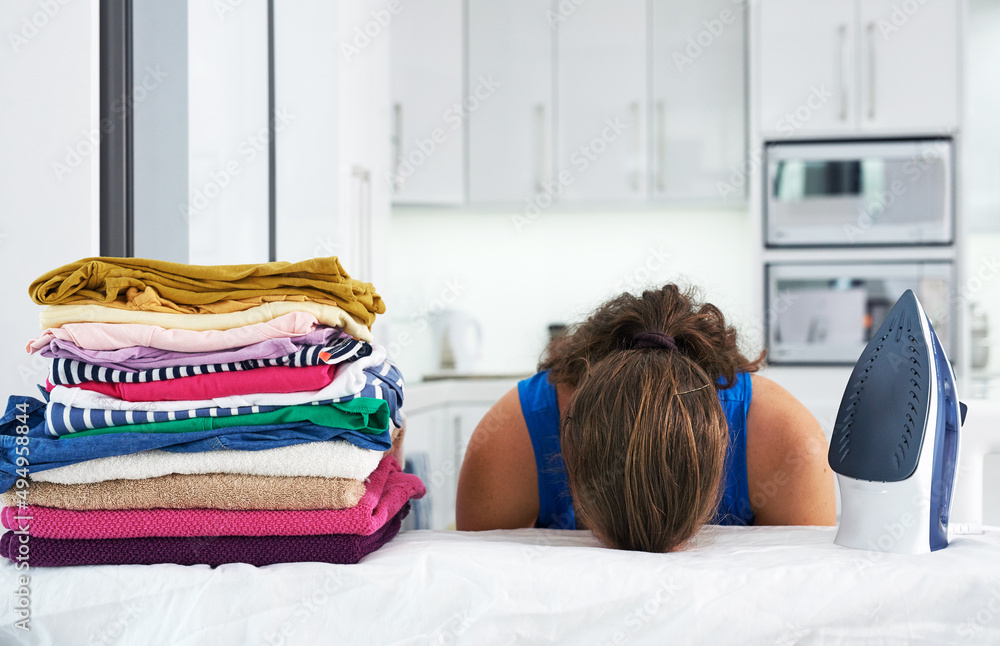 Shes run out of steam. Shot of a young woman with her head down on an ironing board.