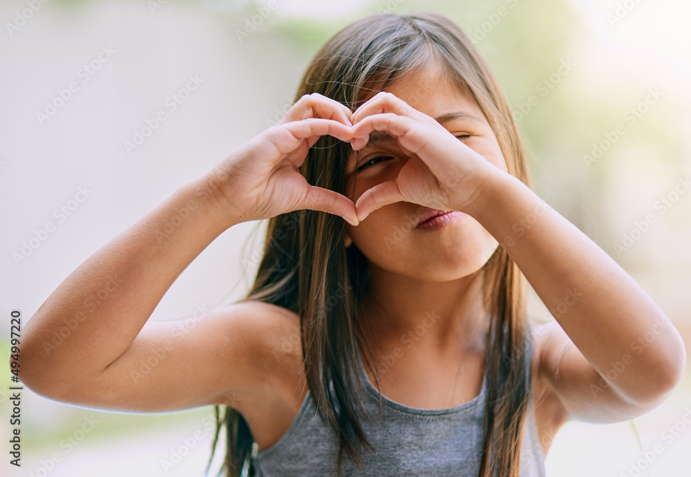 Filling life with love and happiness. Portrait of a little girl making a heart gesture with her hand