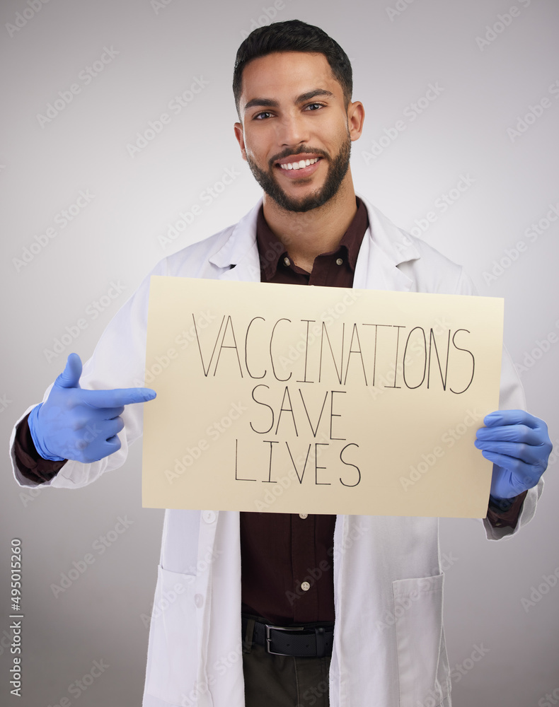 Just got and do it. Shot of a handsome young doctor standing alone in the studio and holding up a po