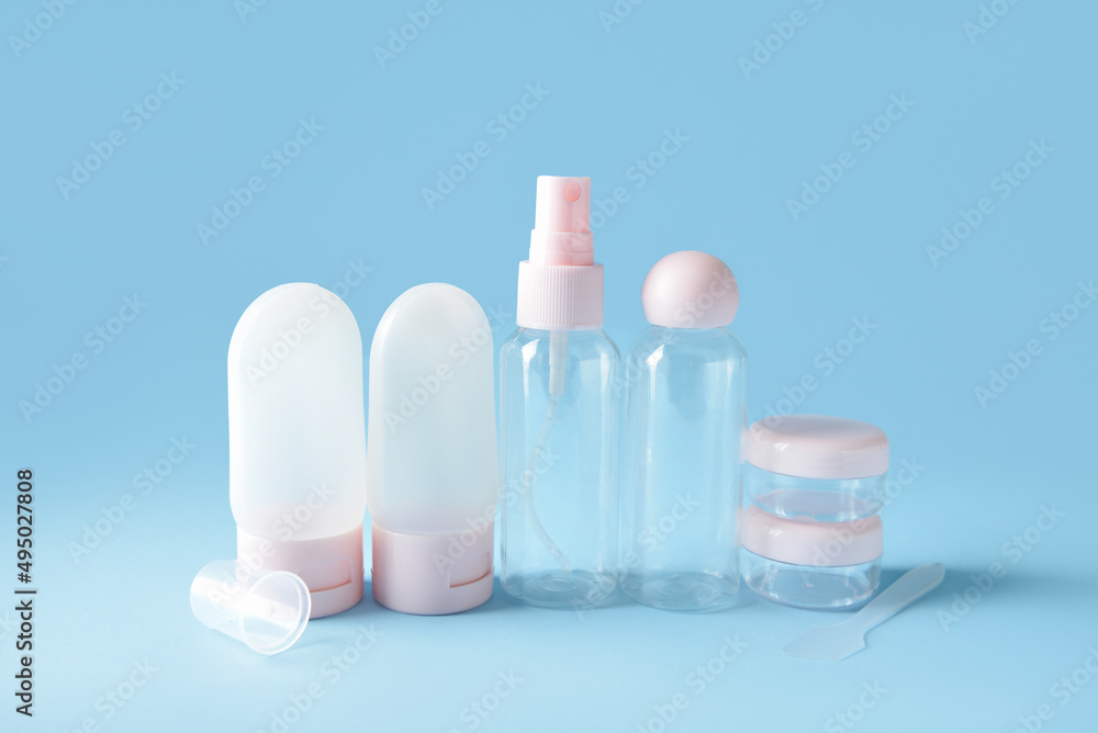 Set of empty travel cosmetic bottles and jars on blue background