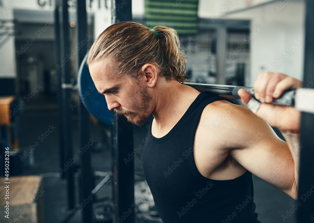 Stop existing and start lifting. Shot of a man lifting weights at the gym.