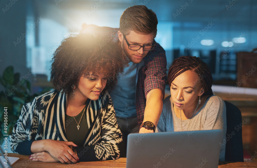 Making a few final changes. Cropped shot of a group of young people working late in the office.