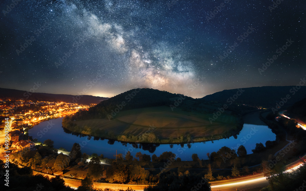 壮丽的夜空，银河系环绕着山丘的河湾，四周环绕着一个发光的太阳