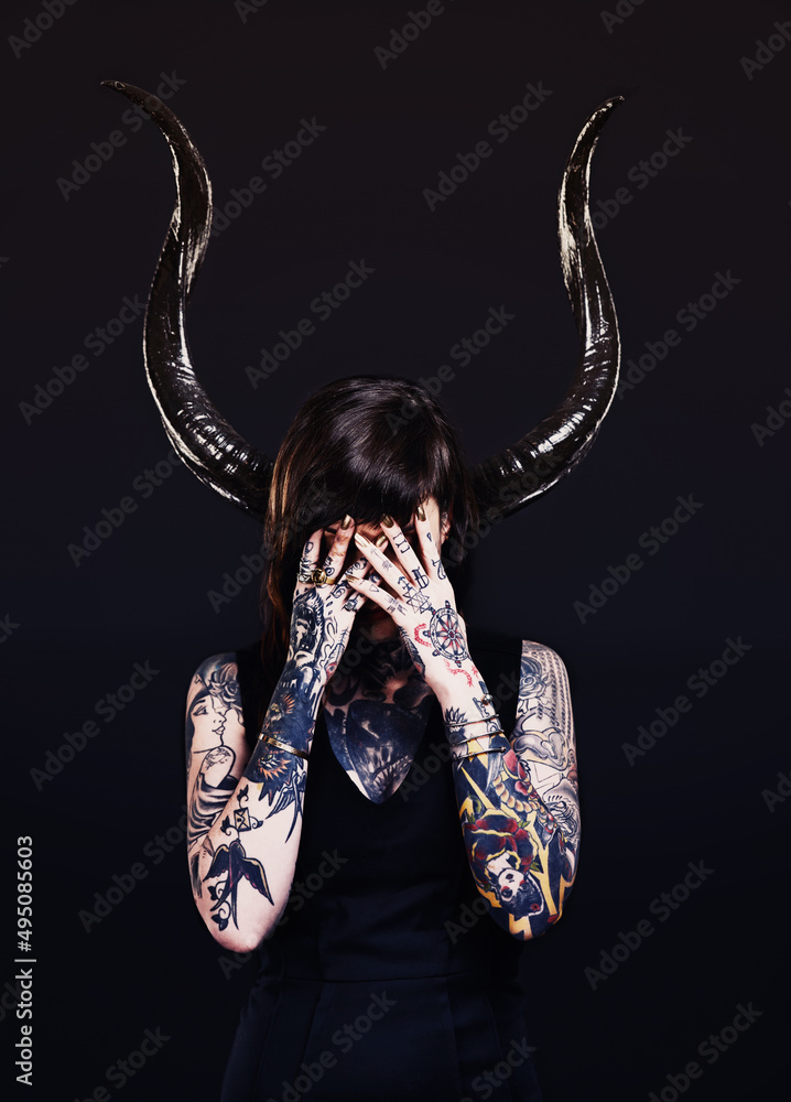 The dark side. Studio shot of a tattooed young woman.