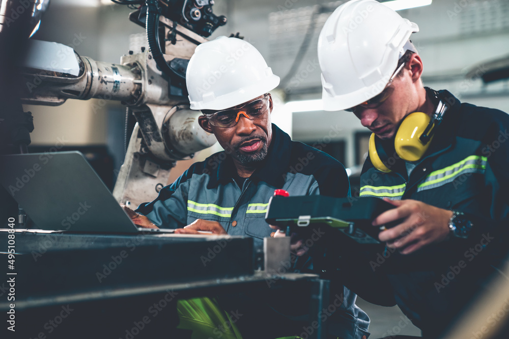 Factory workers working with adept robotic arm in a workshop . Industry robot programming software f