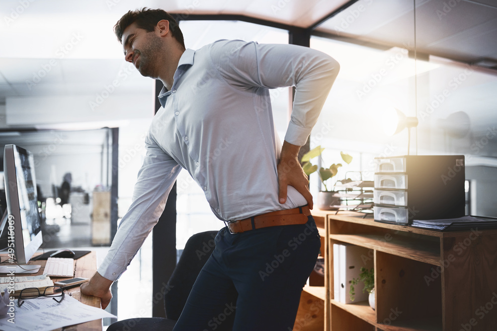 Those cracks dont sound good. Shot of a young businessman suffering with back pain while working lat