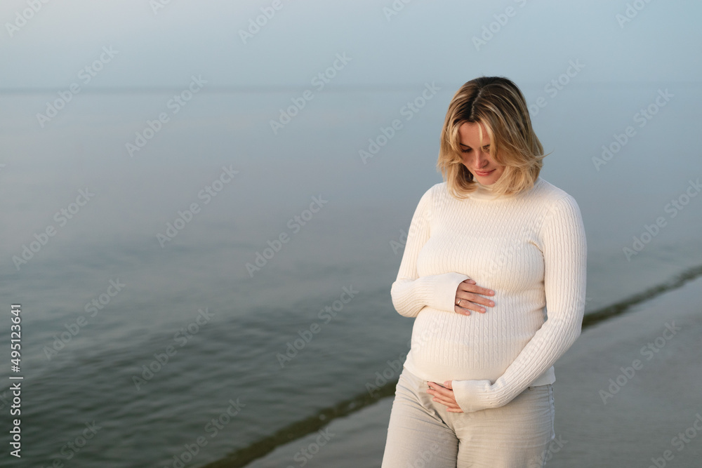 行走在海边沙滩上的自然年轻孕妇