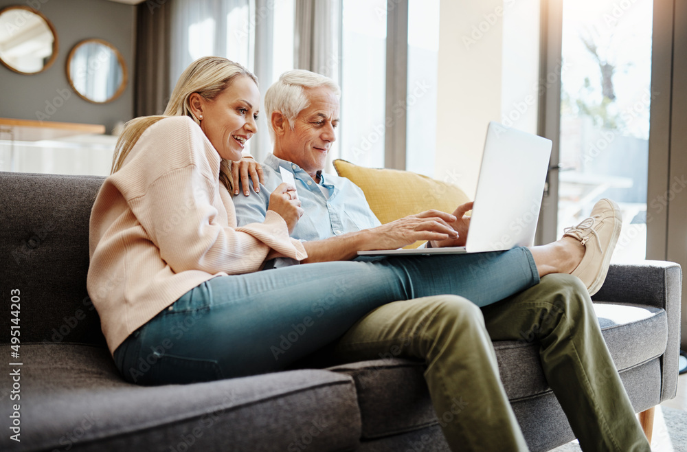 Retirement is a time for treats. Shot of a mature couple using a credit card and laptop on the sofa 