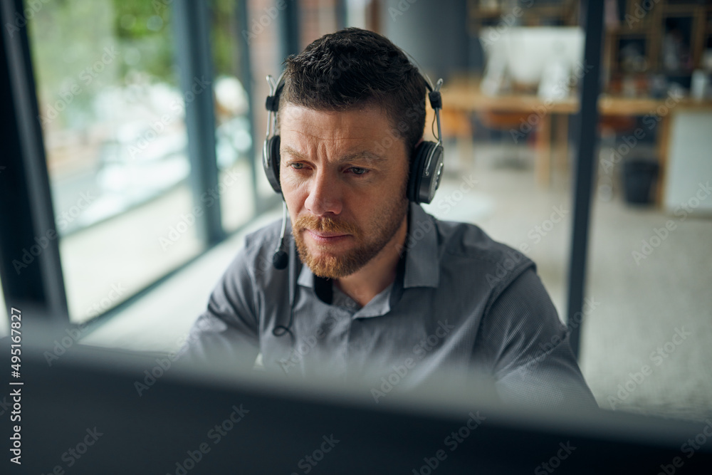 Working hard to resolve all issues for his customers. Shot of a mature man working on a computer in 