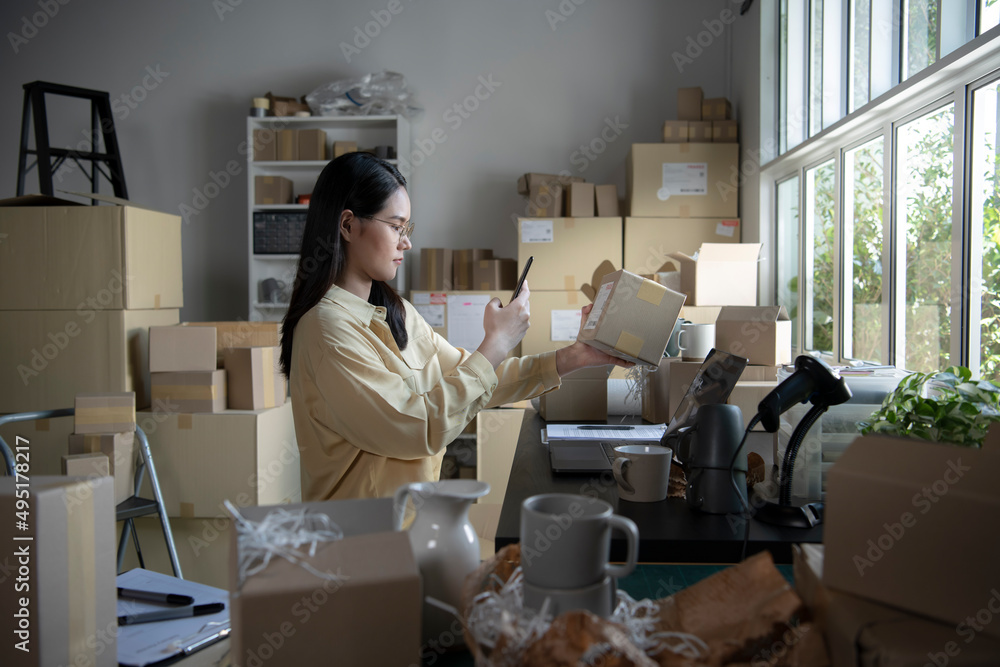 亚洲女性小企业主在智能手机上使用手机应用程序检查包裹箱。仓库工作