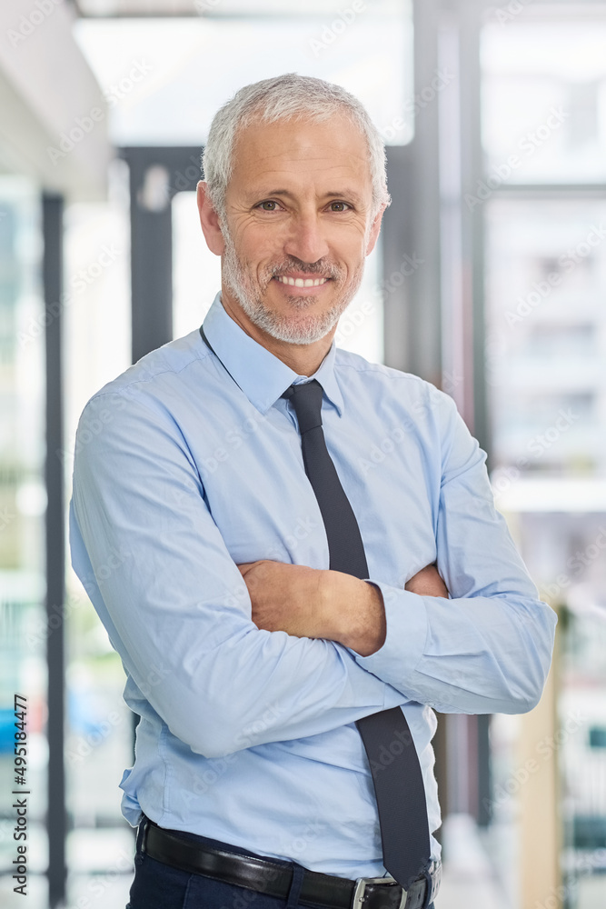 Success is a process. Portrait of a smiling mature executive standing with his arms crossed in an of