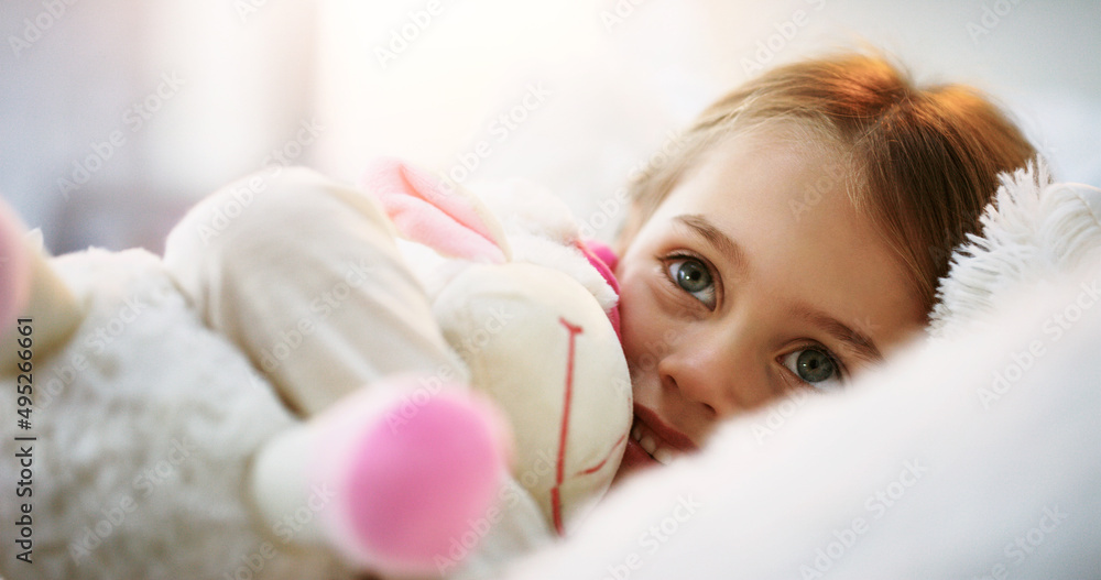 The sweetest face in the world. Shot of an adorable little girl lying in bed with her teddybear at h