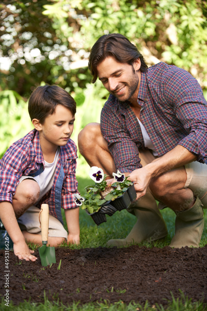 They love gardening together. Shot of a father and son planting flowers in the garden.