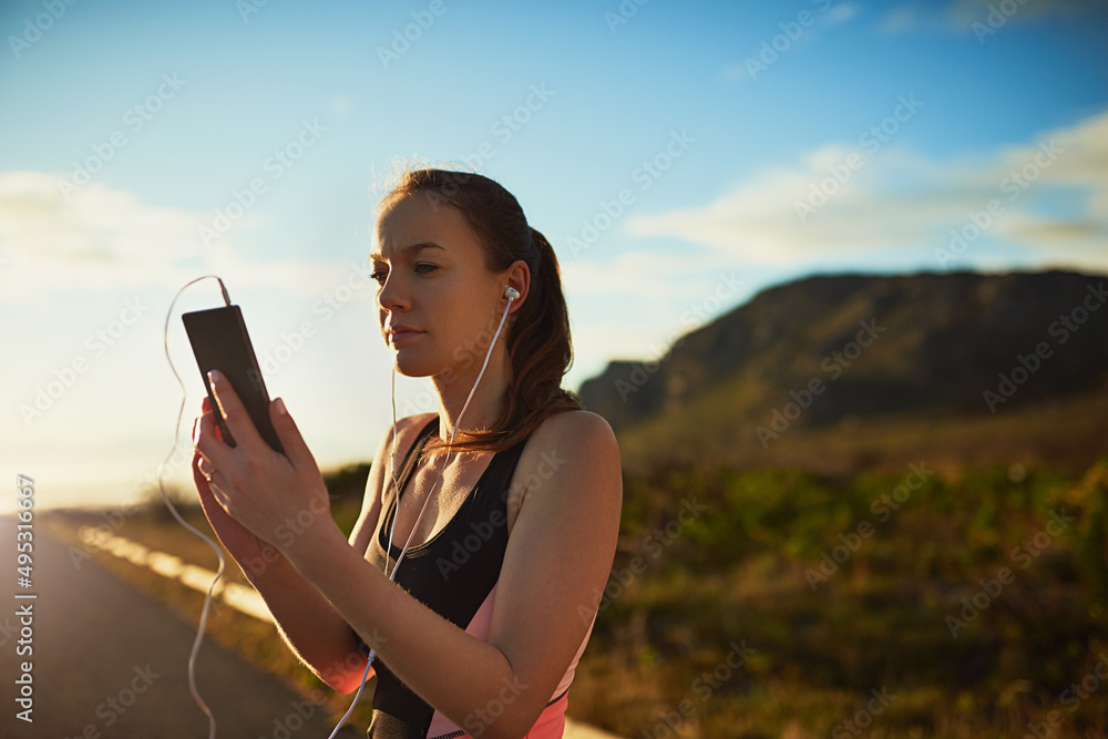 Getting her workout tracks ready. Shot of a sporty young woman organizing her workout playlist outdo