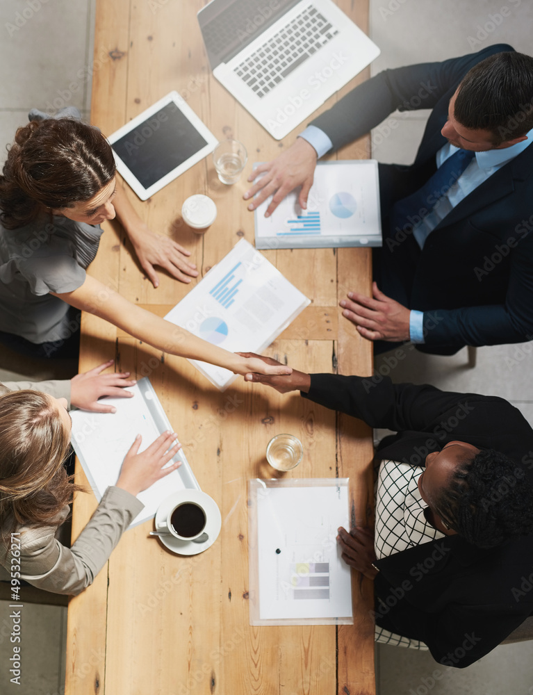 Lets work together to win together. High angle shot of a group of businesspeople shaking hands durin