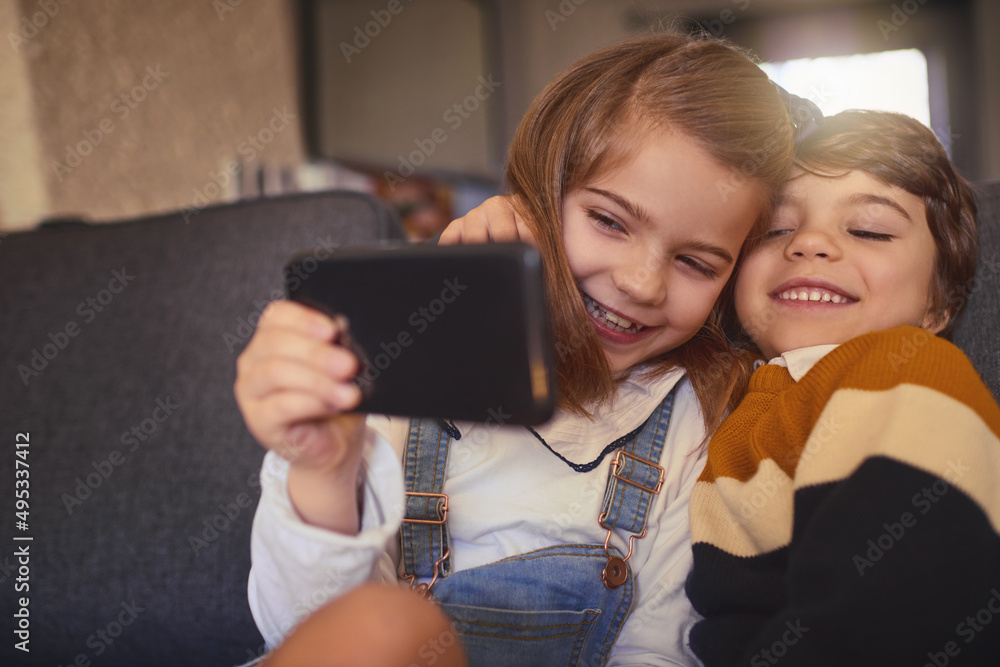 Smile. Cropped shot of an adorable little girl and her younger brother taking selfies while sitting 