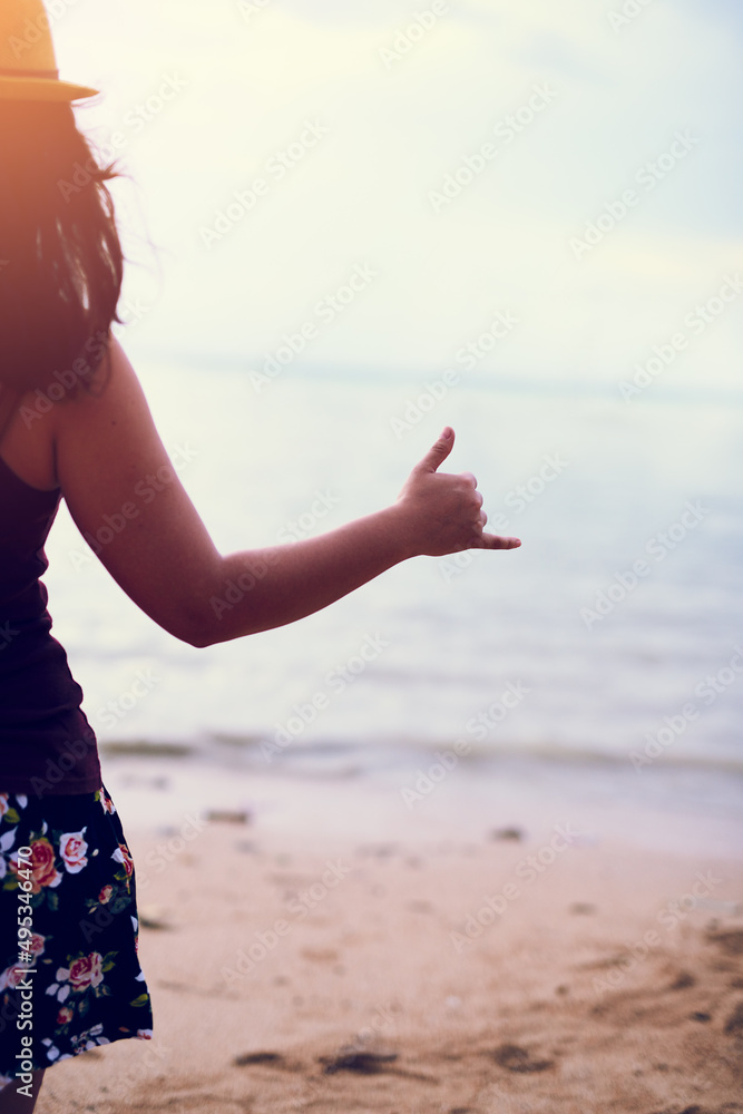 Hang ten. Rearview shot of a young woman at the beach gesturing hang ten.