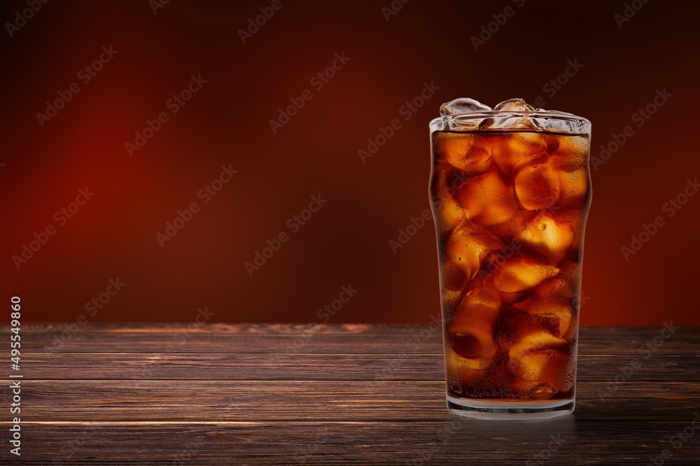 caramel drink, no cola, with ice. Fresh cold sweet drink with ice cubes on red background.