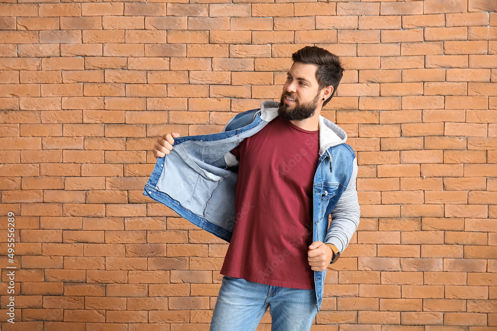 Handsome man in jacket and red t-shirt on brick background