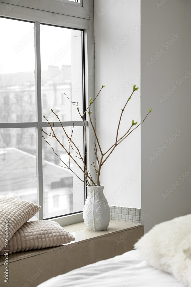 Vase with tree branches on windowsill