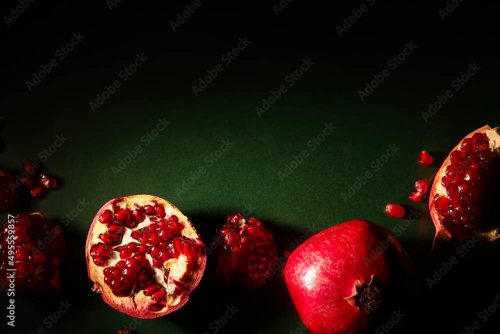 Tasty ripe pomegranates on dark green background