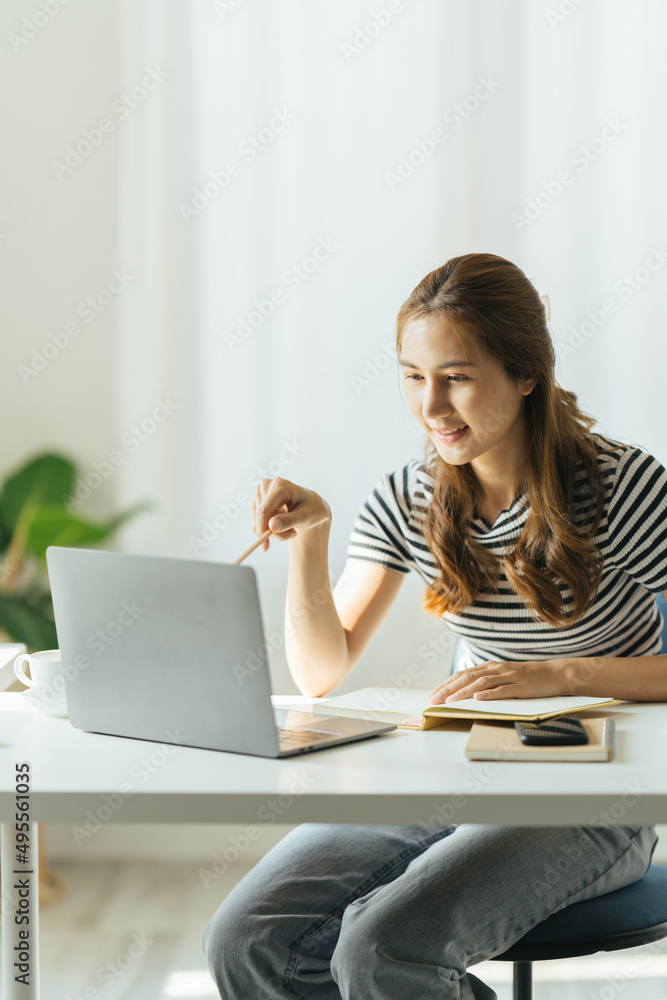 微笑的年轻亚洲女商人在家办公、工作场所使用电脑，快乐的韩国员工世界