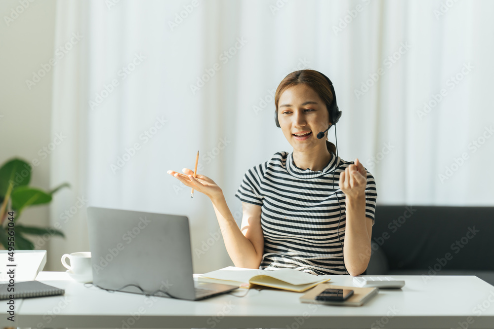 快乐的年轻女商人戴着耳机，享受在线学习，写笔记。微笑创意