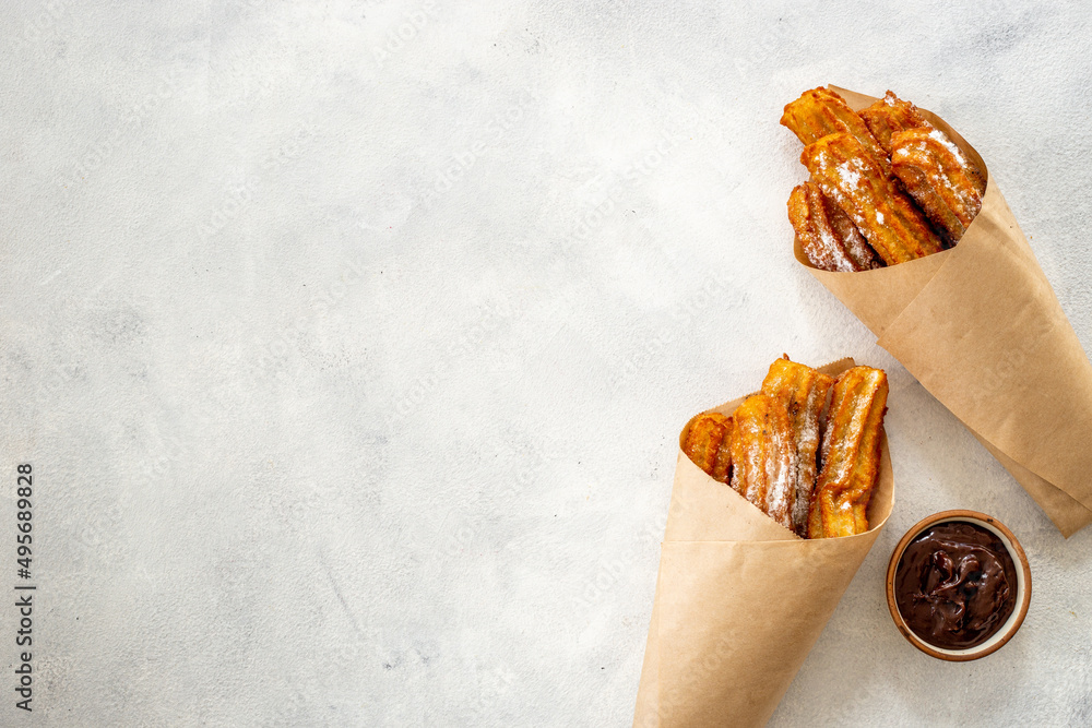 Street food dessert churros in paper bag with sugar