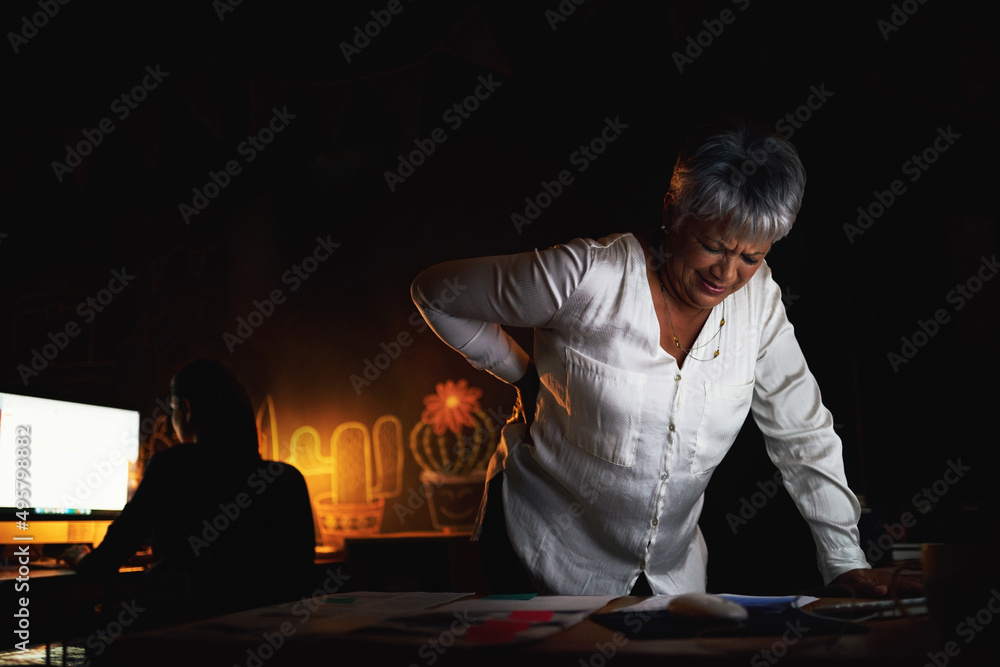 The long hours have creeped into her back. Shot of a mature businesswoman suffering with back pain w